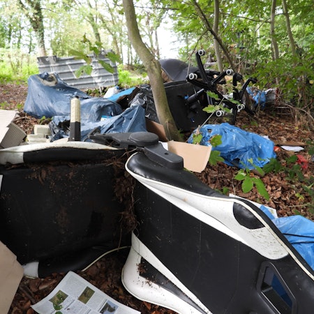 Auf dem Bild ist ein großer Müllhaufen im Wald zu sehen.