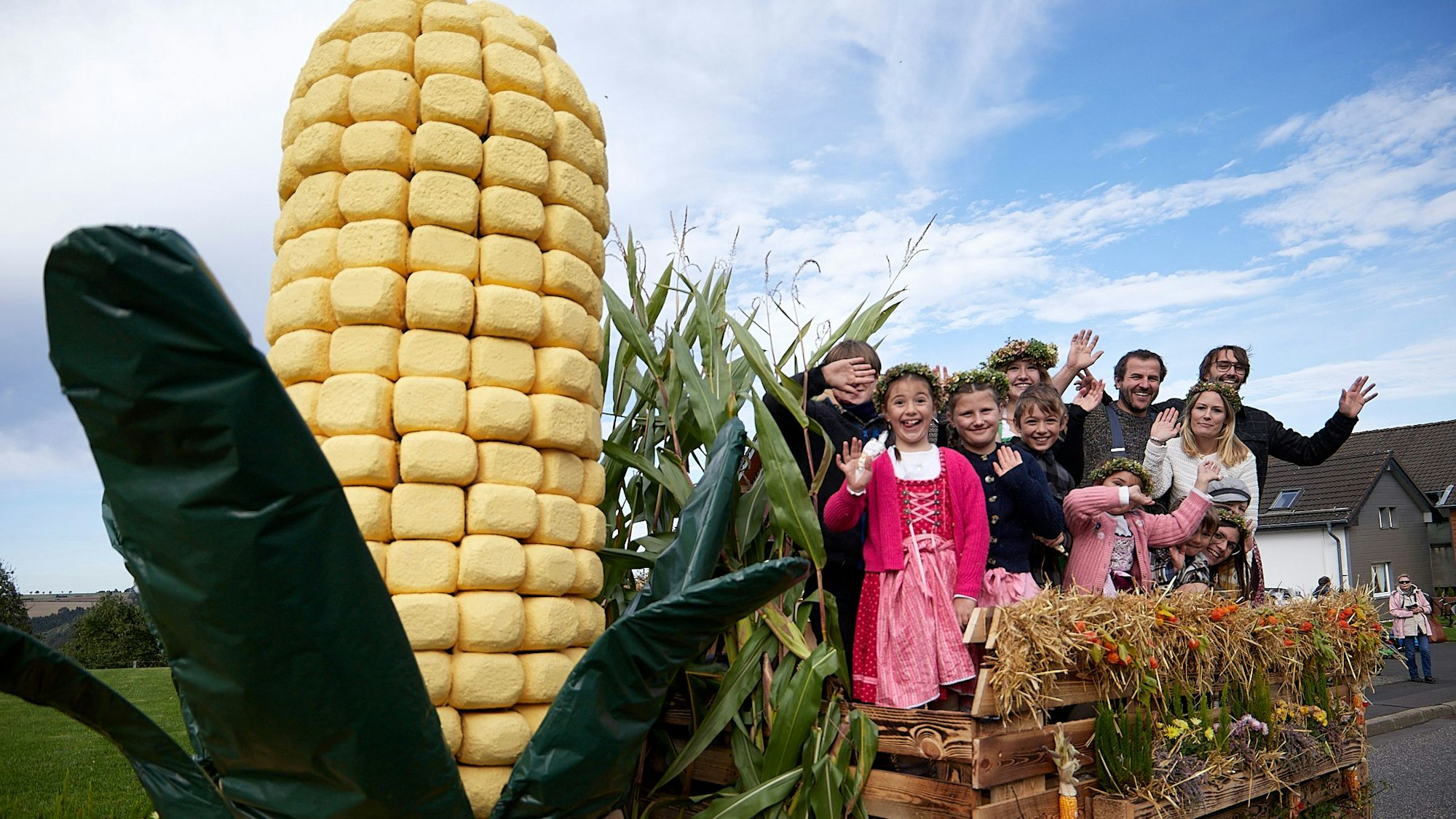 Blickfang auf dem Wagen ist ein überdimensionaler Maiskolben mit Blättern. Die Familienmitglieder winken fröhlich.
