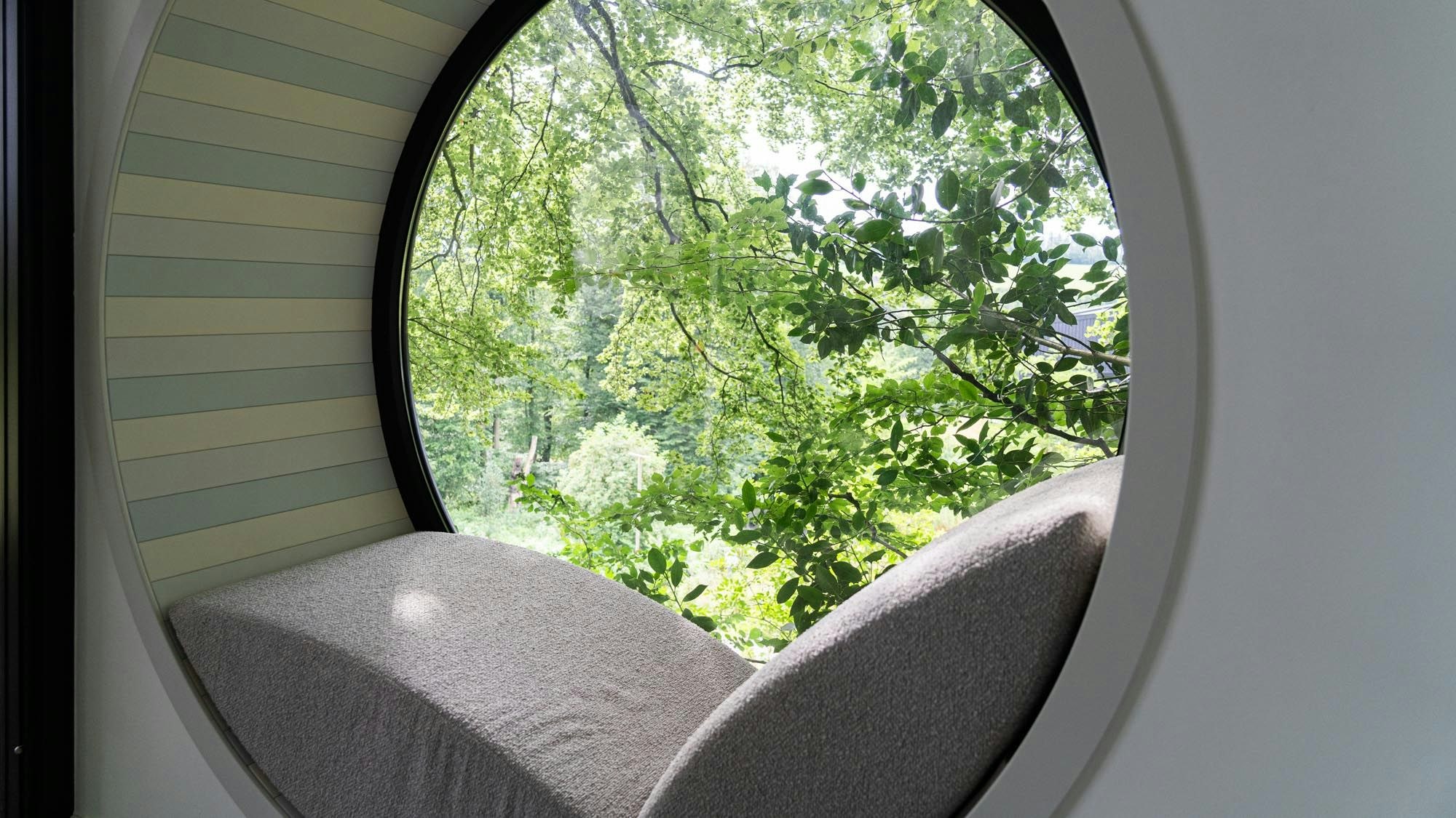 Ein gemütlicher Sitzplatz in einem großen Bullauge gibt den Blick auf den Wald frei.