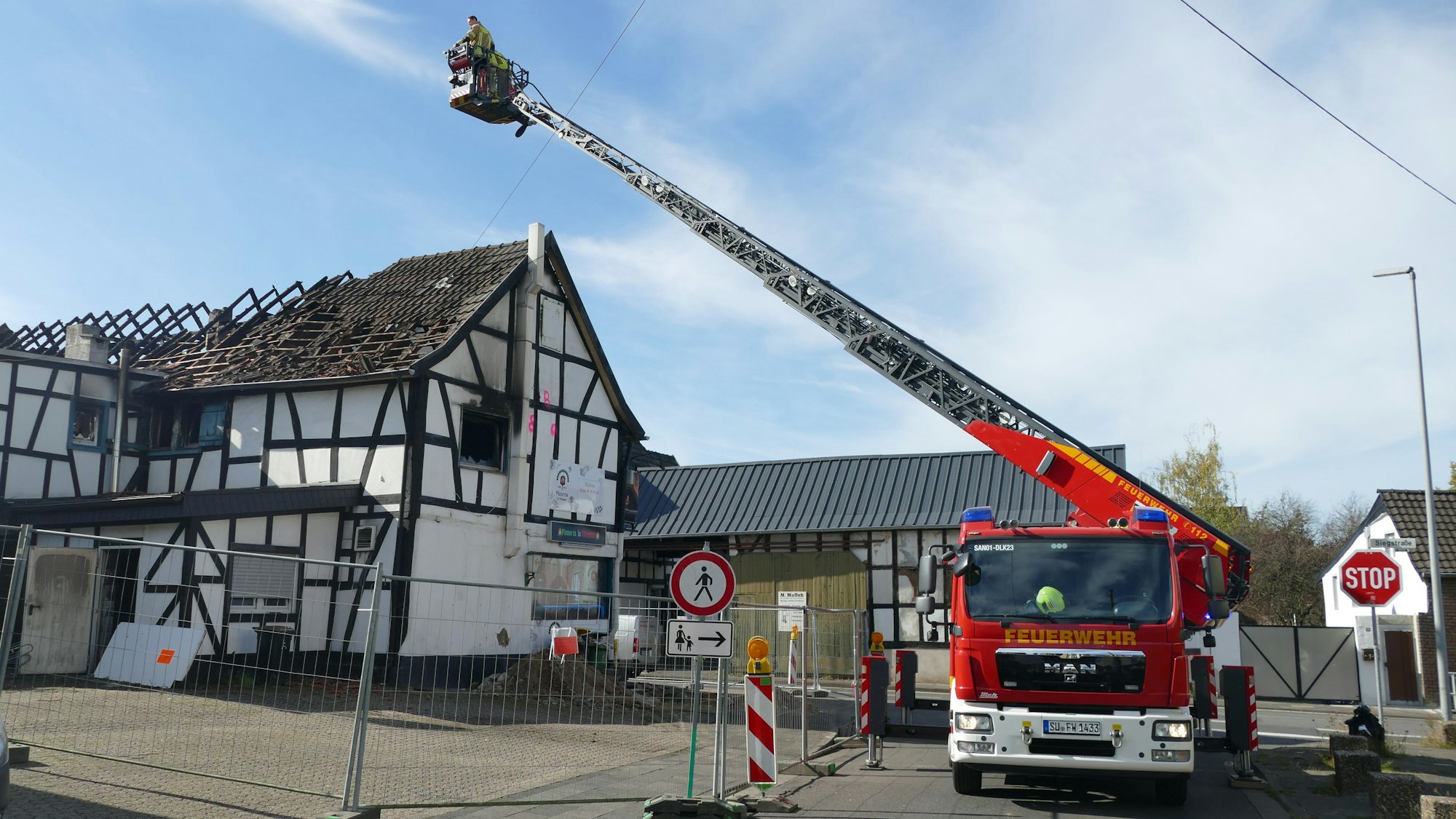 Brandermittler der Polizei untersuchen das Dach vom Korb einer Drehleiter der Feuerwehr aus.