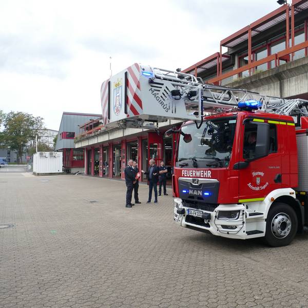 Eine Drehleiter der Feuerwehr fährt aus einem Wachgebäude.
