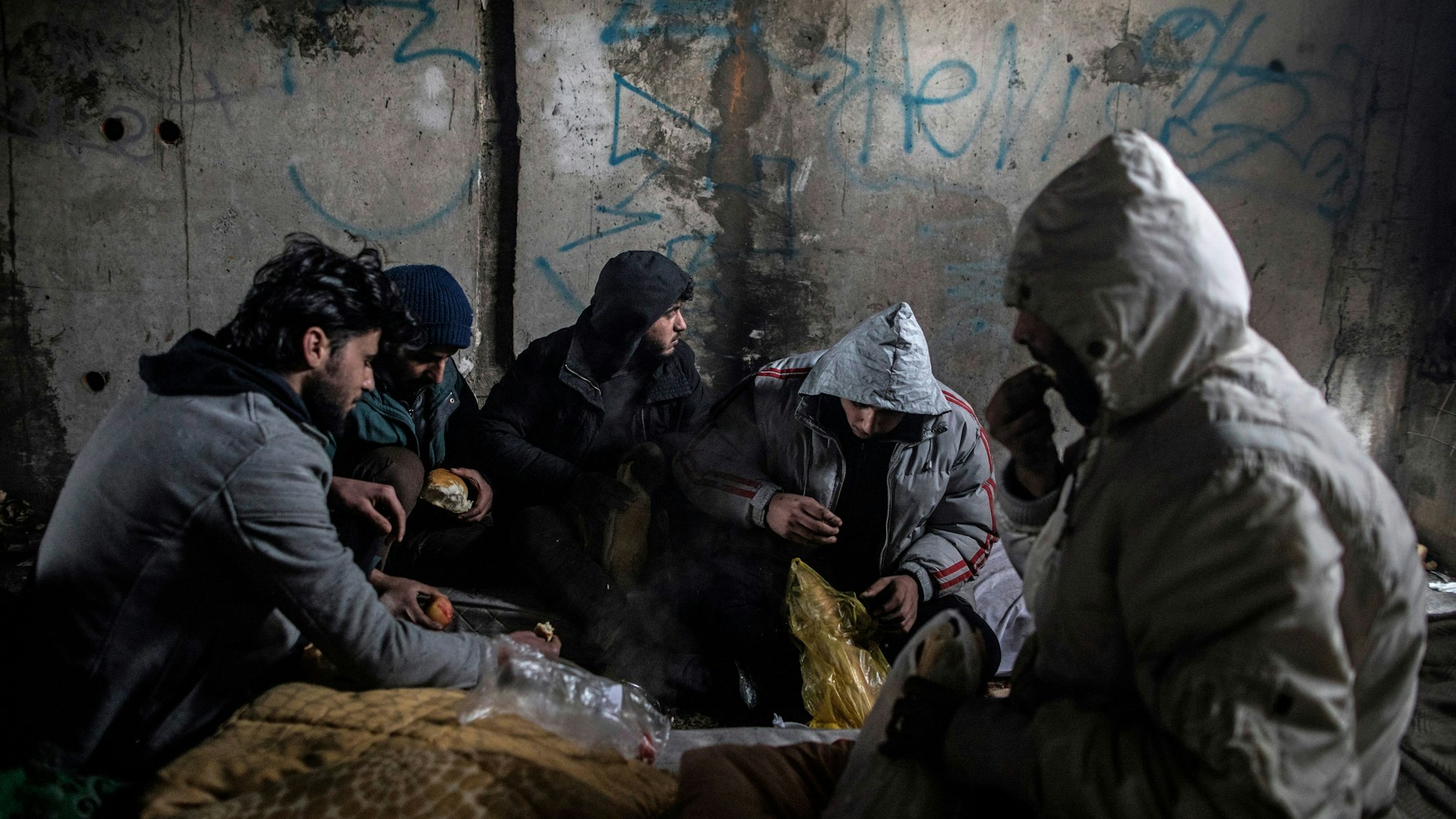 Eine Gruppe syrischer Migranten frühstückt in einem verlassenen Gebäude, in dem sie Unterschlupf gesucht hatten.