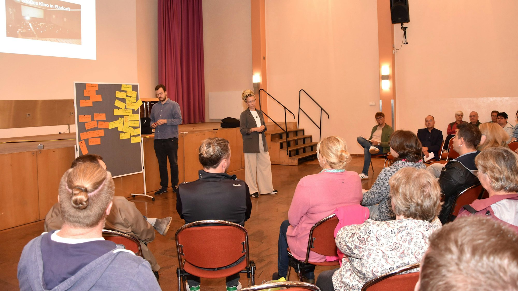 Menschen sitzen in einem Saal.