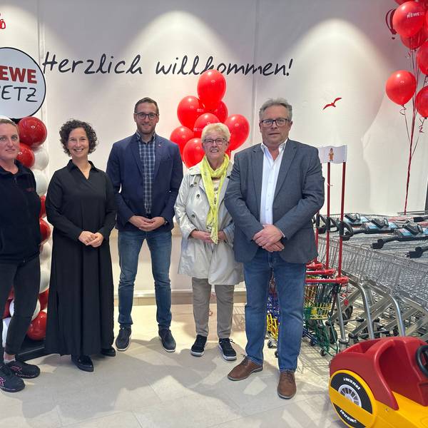 Fünf Menschen stehen zu einem Gruppenfoto aufgestellt vor weißen und roten Luftballons.