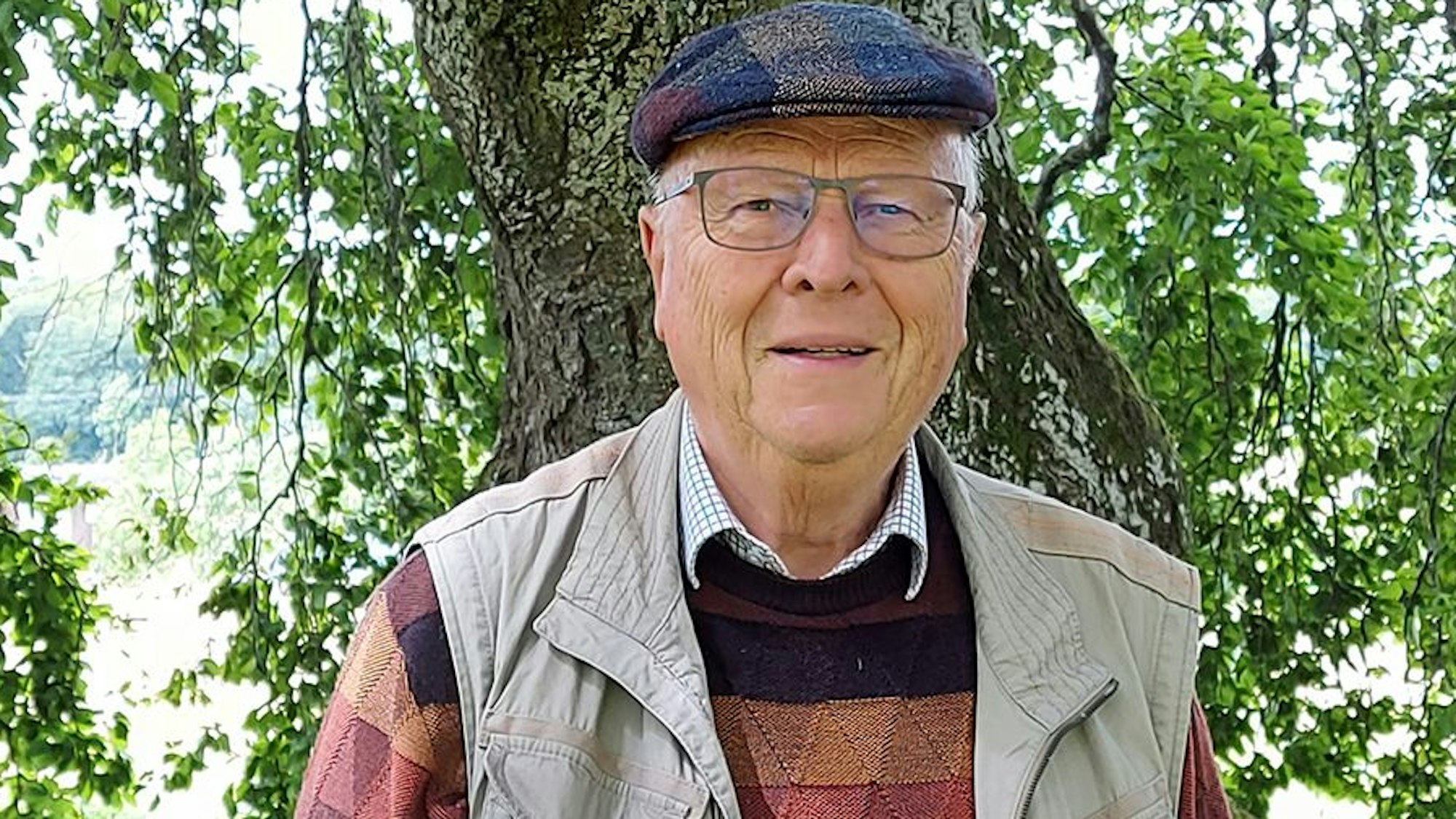 Das Bild zeigt Professor Wolfgang Schumacher vor einem Baum.