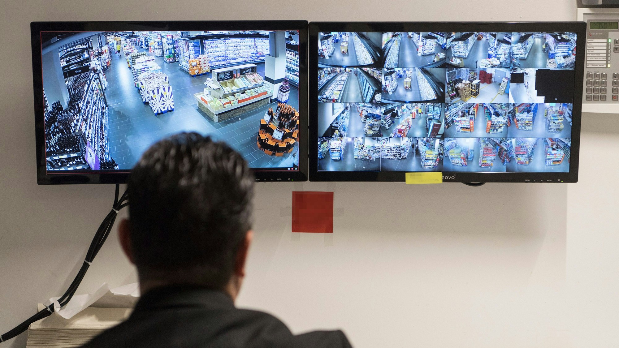 Ein Ladendetektiv sitzt vor Überwachungsmonitoren eines Supermarktes. (Symbolbild)