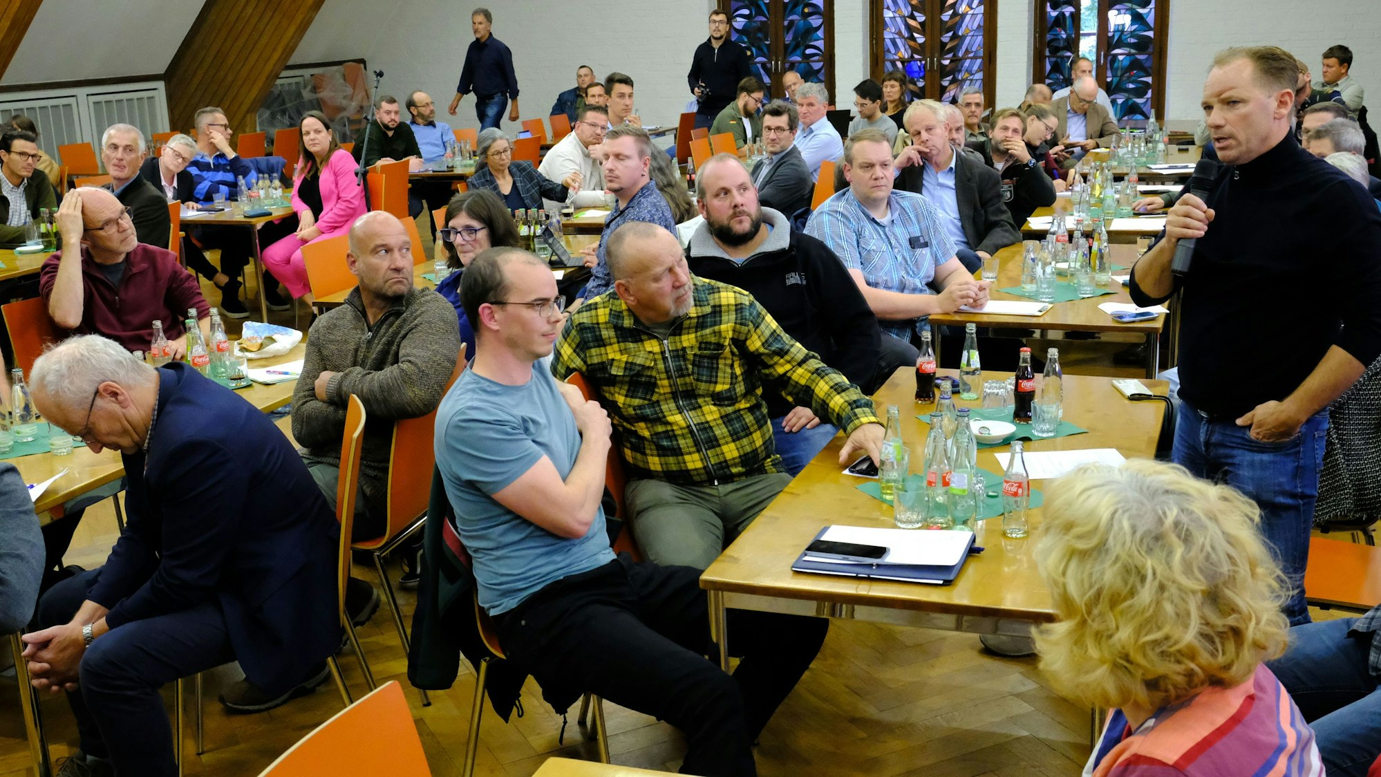 In der Aula der Landwirtschaftskammer in Düren sitzen zahlreiche Teilnehmer einer Diskussionsveranstaltung an Tischen.