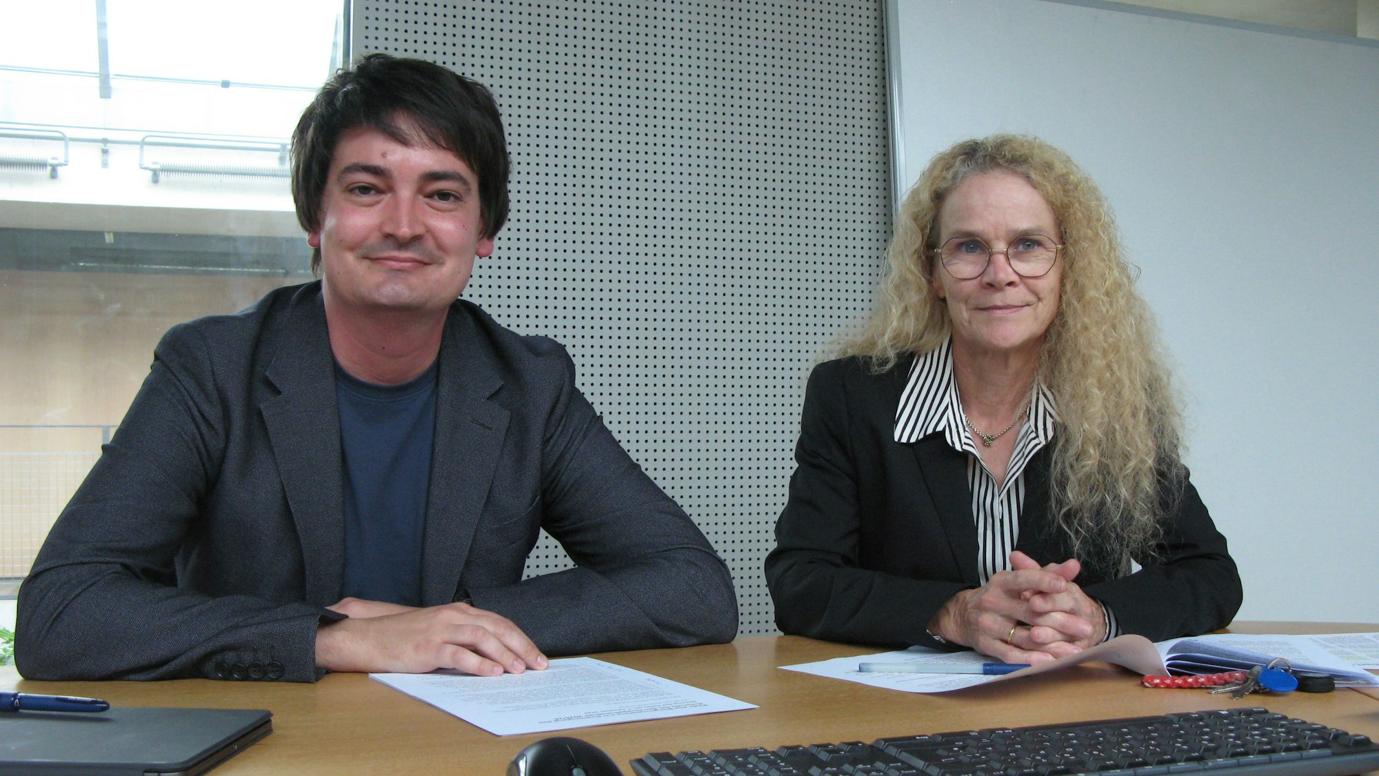 Der Bürgermeister und die Kämmerin sitzen mit Papieren und Ladtops an einem Tisch.