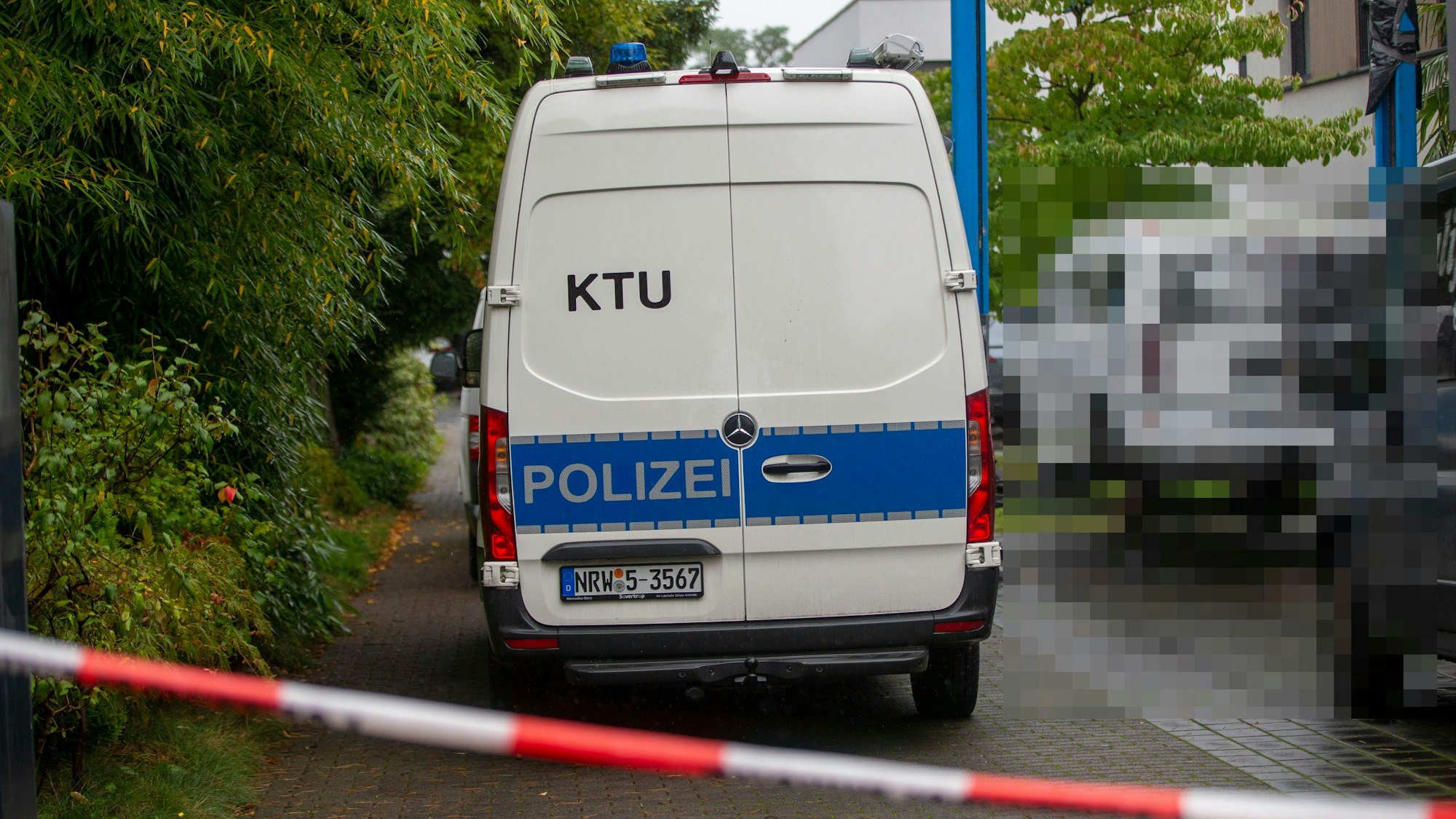 Ein Einsatzfahrzeug der KTU (Kriminaltechnische Untersuchung) steht vor dem Wohnhaus im Stadtteil Hahnwald.