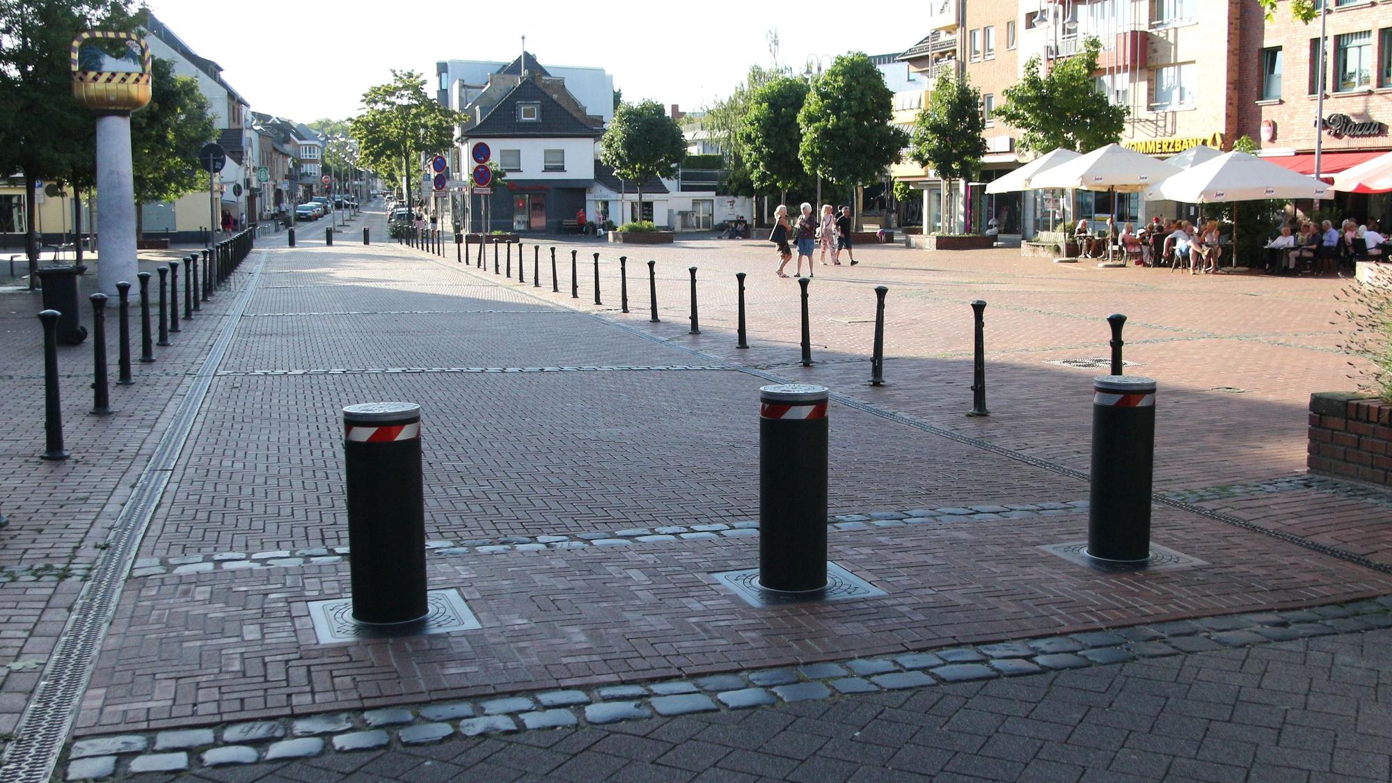 Drei Poller versperren einen Straßenabschnitt.