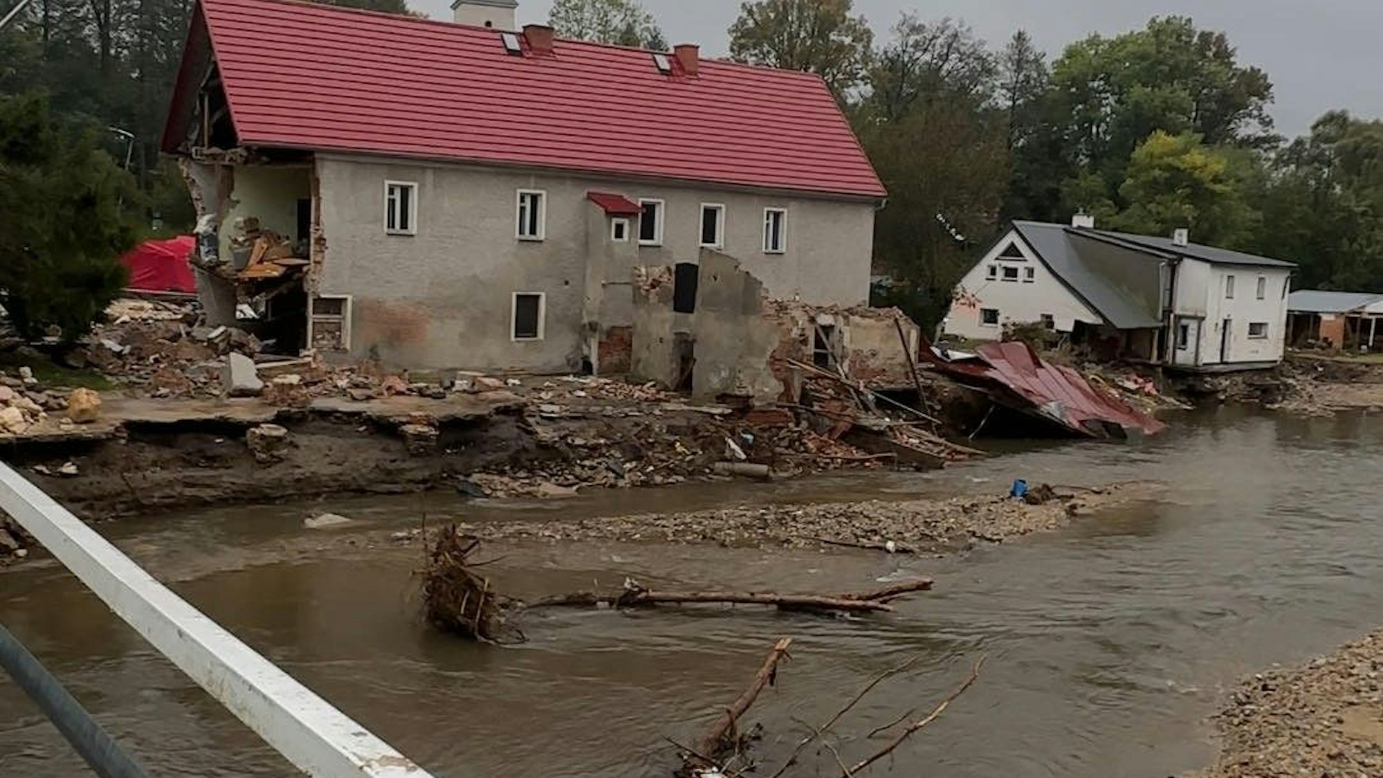 Das Bild zeigt zwei stark in Mitleidenschaft gezogene Häuser an einem Fluss in Polen.