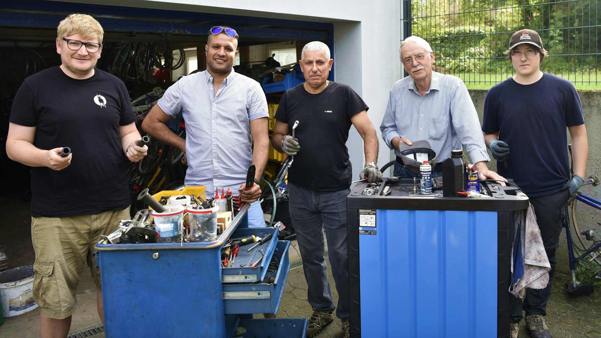 Theo Trösser (2.v.r.) steht mit seinen Kollegen von der Fahrradwerkstatt für Bedürftige der Evangelischen Kirche an zwei Werkzeug-Roll-Containern.