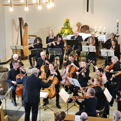 Das Orchester spielt im Altarraum, der mit Blumen und Kerzen geschmückt ist.