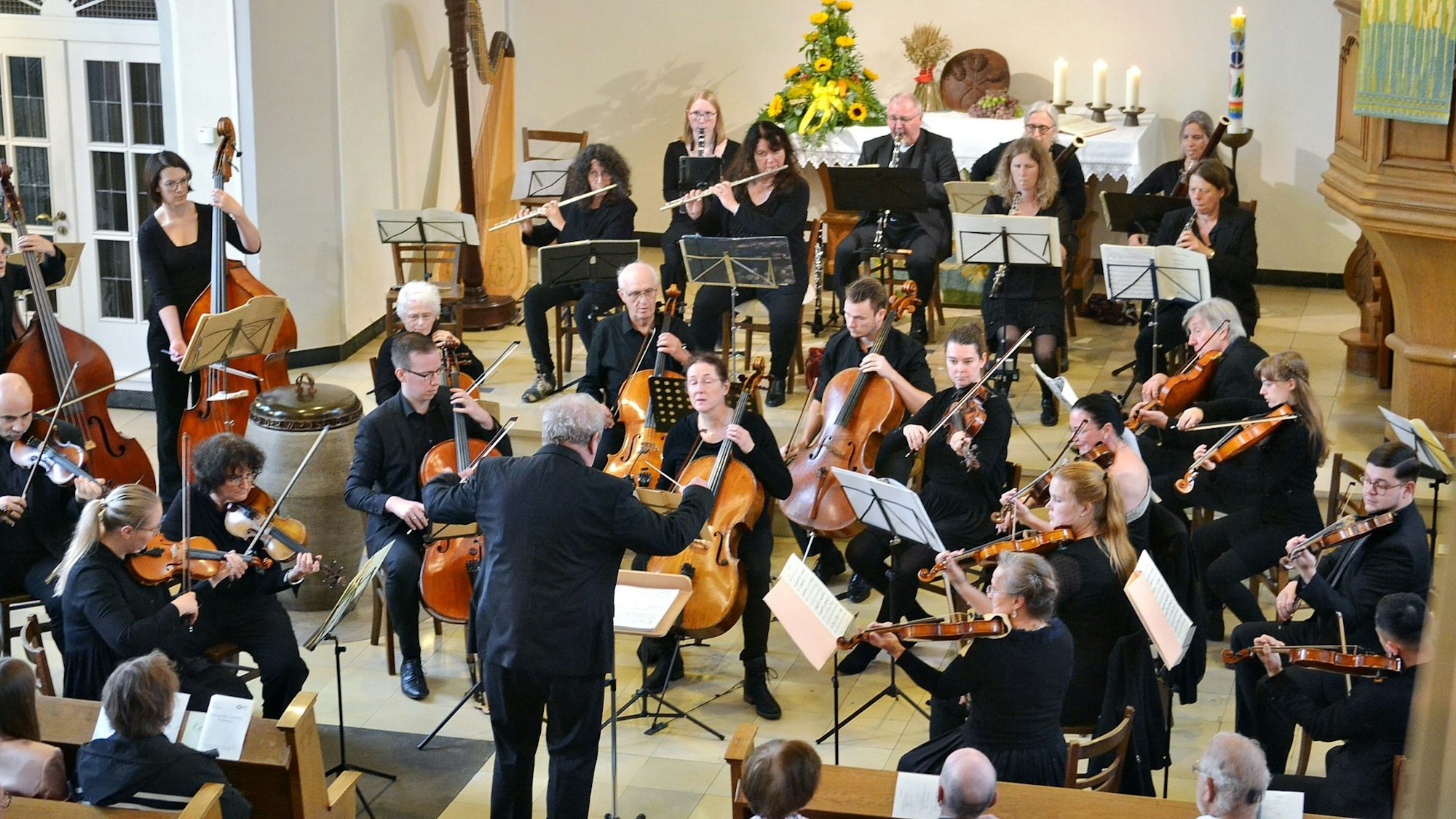Das Orchester spielt im Altarraum, der mit Blumen und Kerzen geschmückt ist.