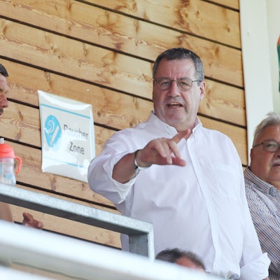 Werner Wolf spricht mit Lukas Podolski auf einer Tribüne.