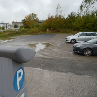Ein Blick auf den Parkplatz mit einer Reihe freier Plätze, im Vordergrund ein Parkscheinautomat.