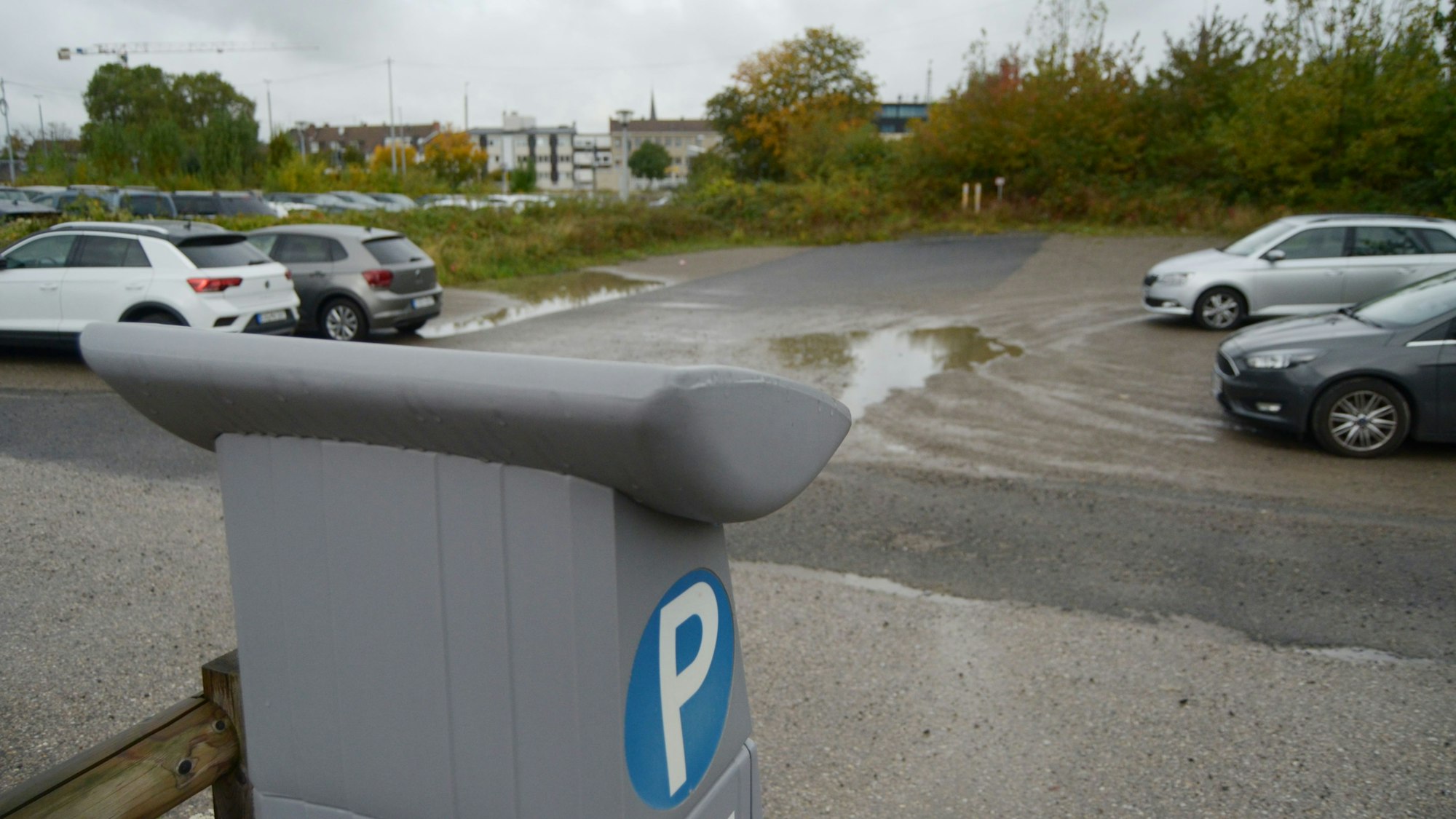 Ein Blick auf den Parkplatz mit einer Reihe freier Plätze, im Vordergrund ein Parkscheinautomat.