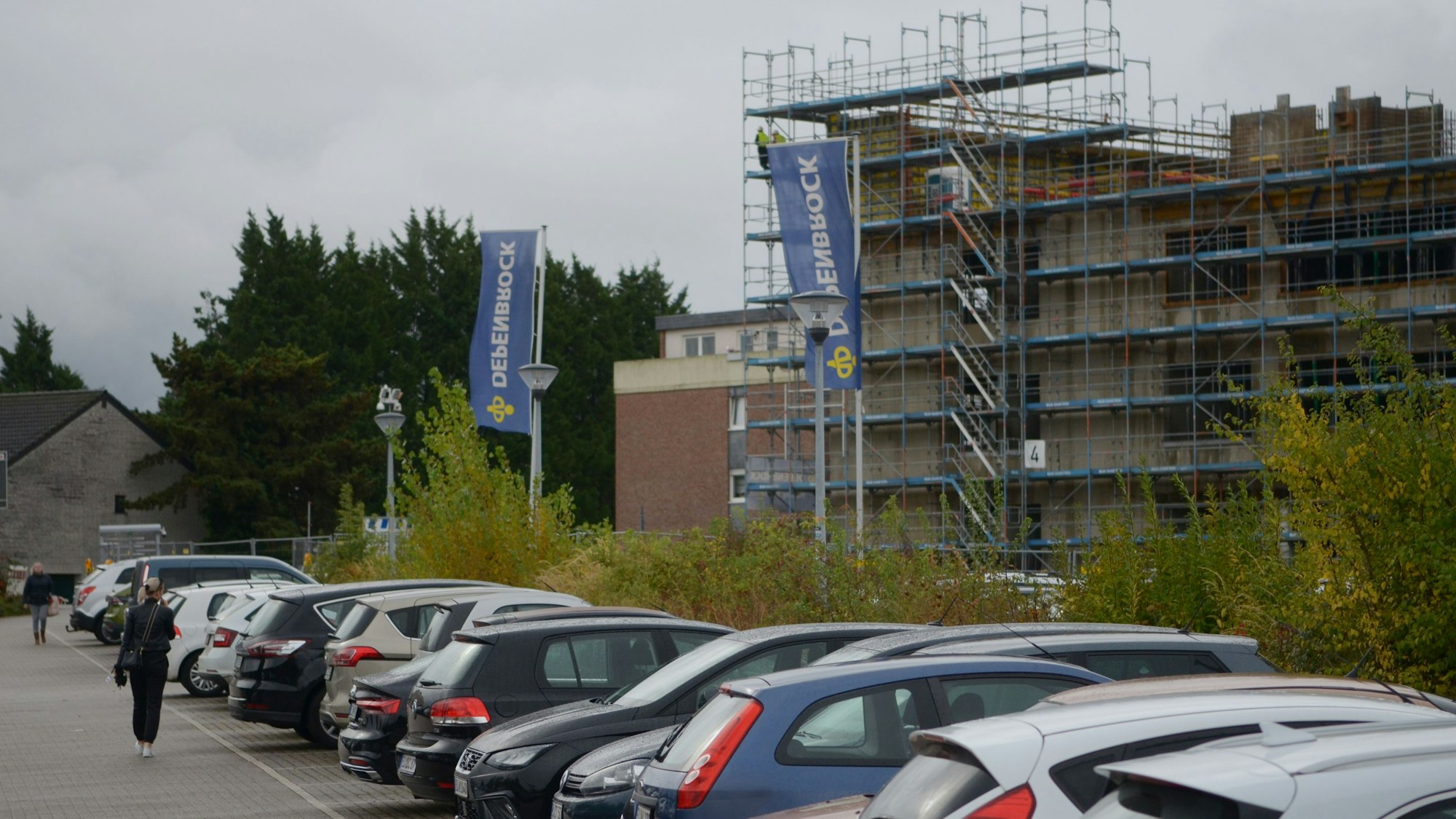 Hinter einer Reihe von Autos wächst das künftige Rathaus in die Höhe.
