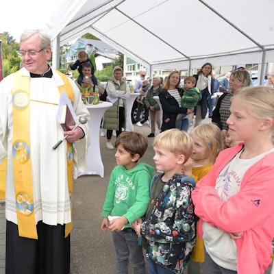 Pastor Franz Gerards segnete die neue Kita Himmelzelt in Rösrath-Forsbach. Er durchschnitt ein rotes Band und eröffnete so symbolisch den Container-Bau, in dem die Kita provisorisch unterkommt.