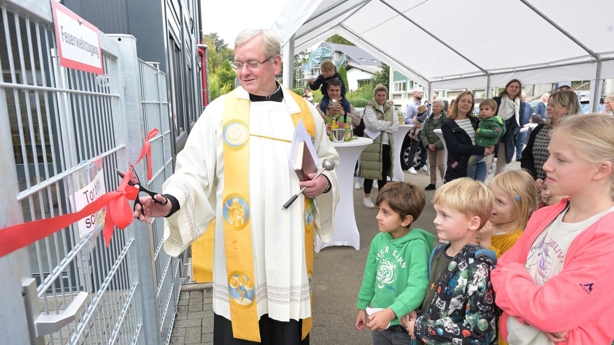 Pastor Franz Gerards segnete die neue Kita Himmelzelt in Rösrath-Forsbach. Er durchschnitt ein rotes Band und eröffnete so symbolisch den Container-Bau, in dem die Kita provisorisch unterkommt.