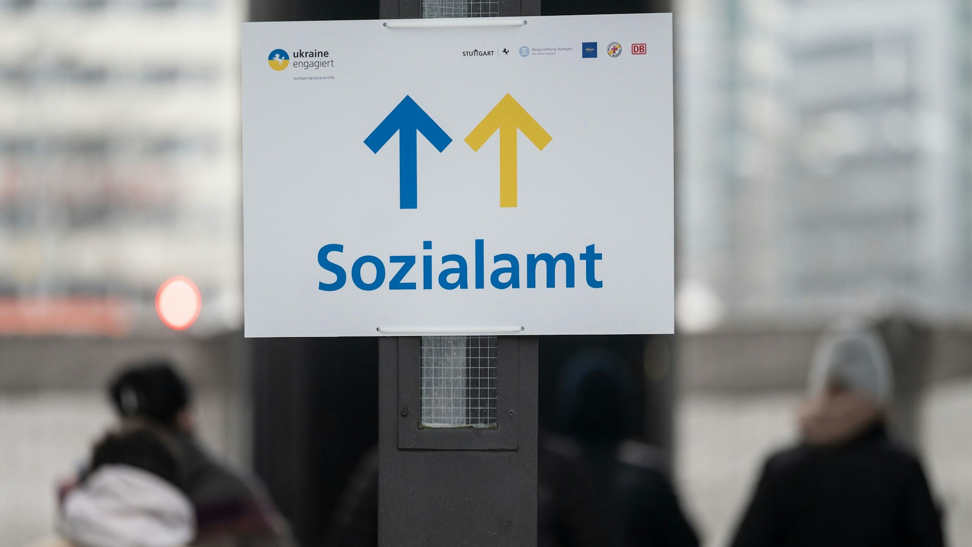 Geflüchtete stehen vor einem Schild mit dem Aufdruck Sozialamt