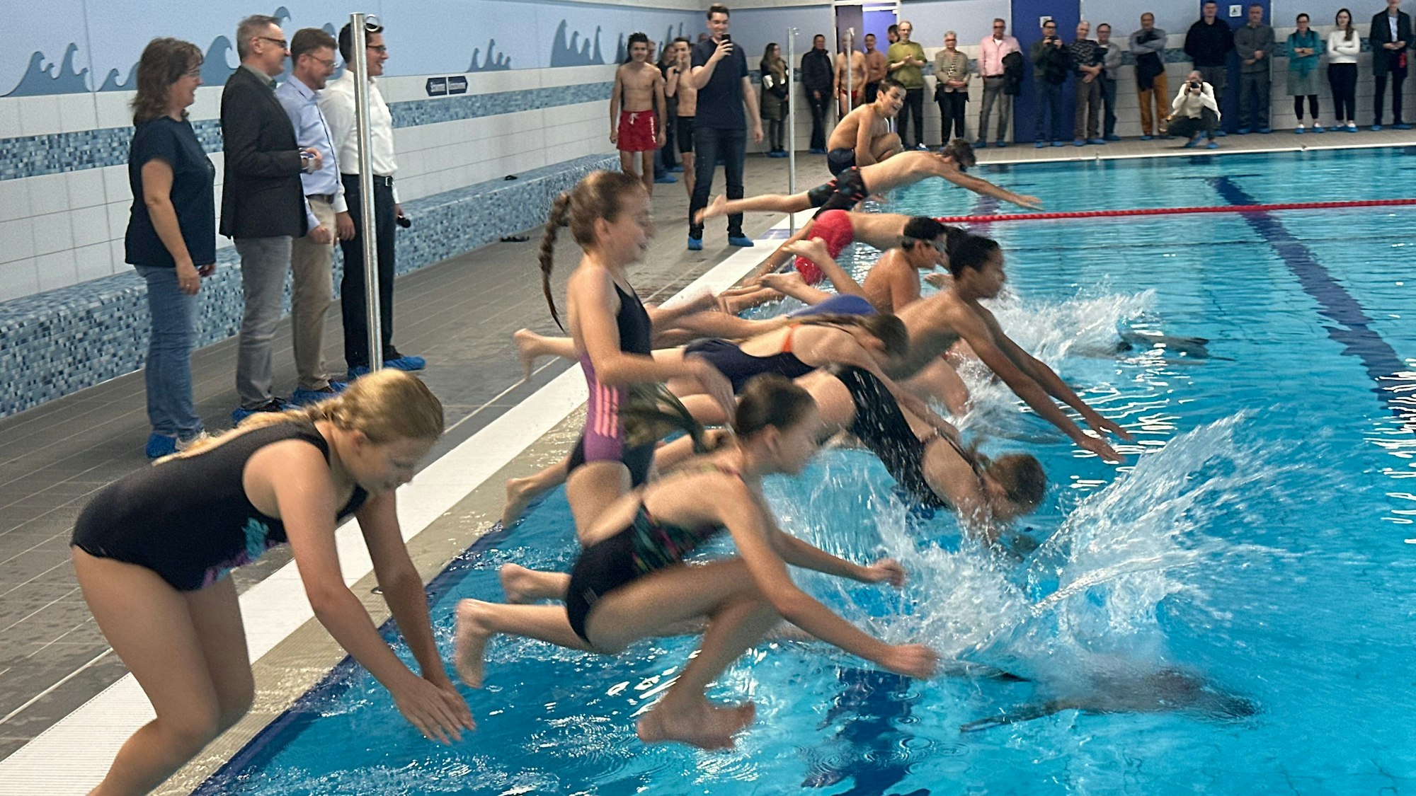 Das offizielle Anschwimmen: Kinder und Jugendliche springen vergnügt ins Becken des des Hallenbades in Niederpleis. Es wurde für acht Millionen Euro saniert.