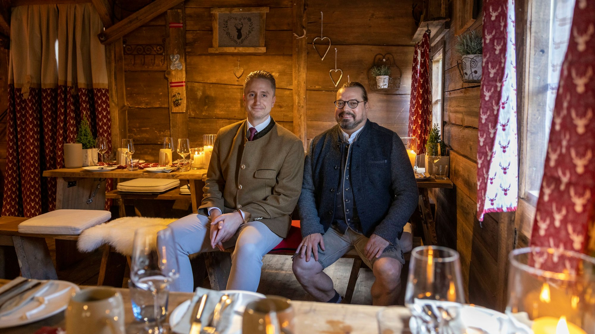 Hoteldirektor Alexander Lalk (l.) und Küchenchef Darrick Carter sitzen in einer gemütlich eingerichteten Holzhütte.