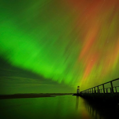Nordlichter am Himmel über der Schutzhütte auf dem Damm, der zur Holy Island in Northumberland an der Nordostküste Englands führt, zu sehen.