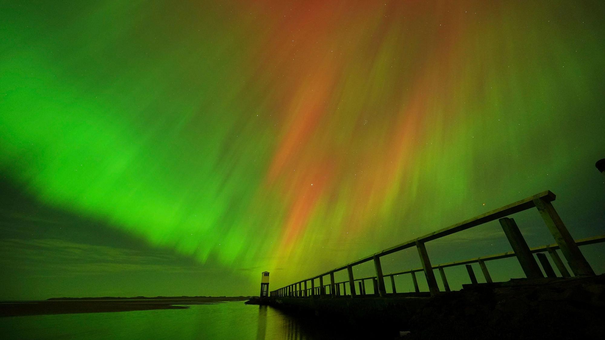 Nordlichter am Himmel über der Schutzhütte auf dem Damm, der zur Holy Island in Northumberland an der Nordostküste Englands führt, zu sehen.