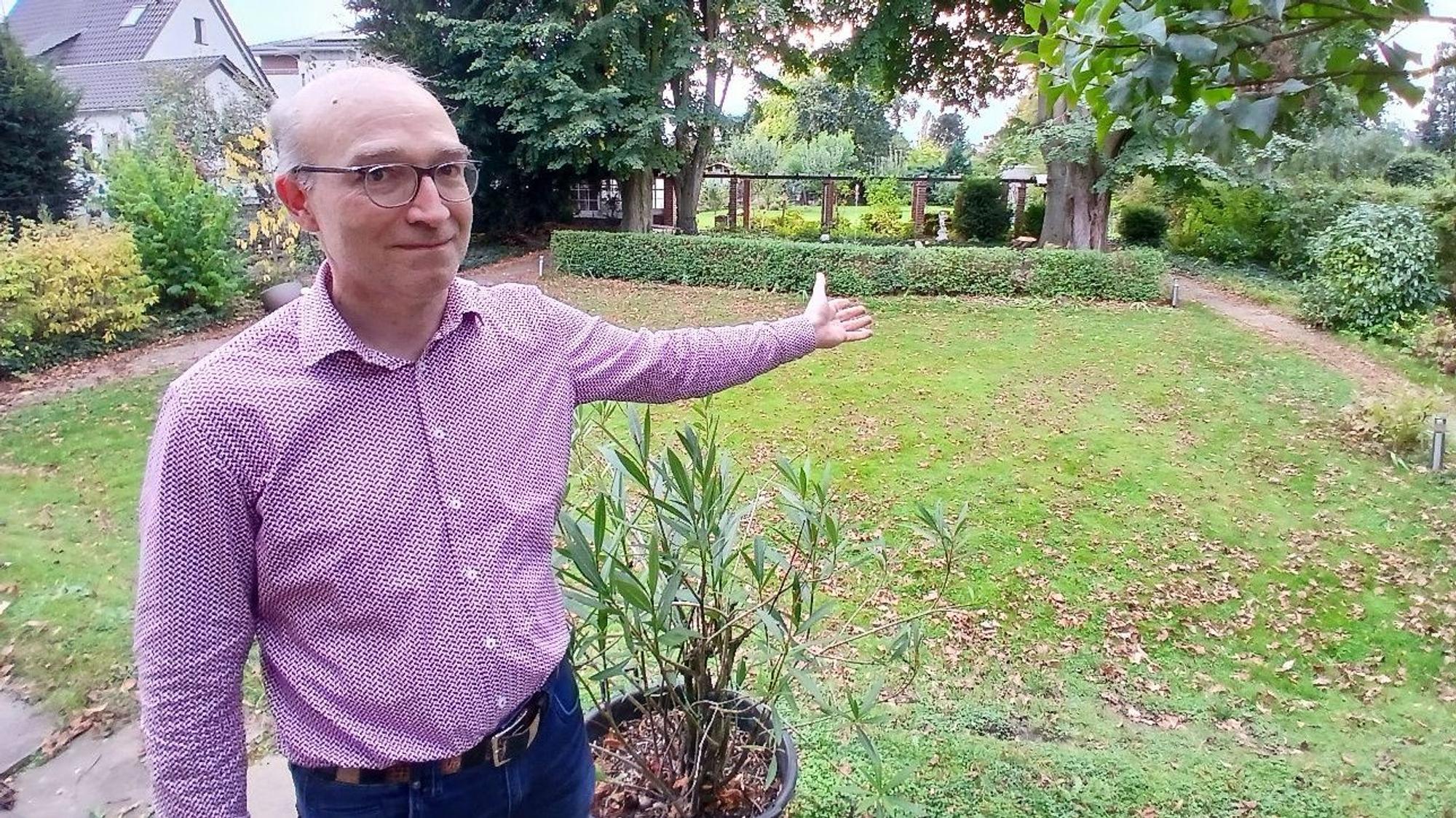 Ein Mann zeigt in seinen Garten