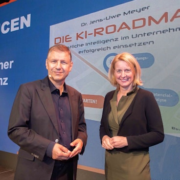 Eine Frau und ein Mann stehen vor einer Präsentationswand