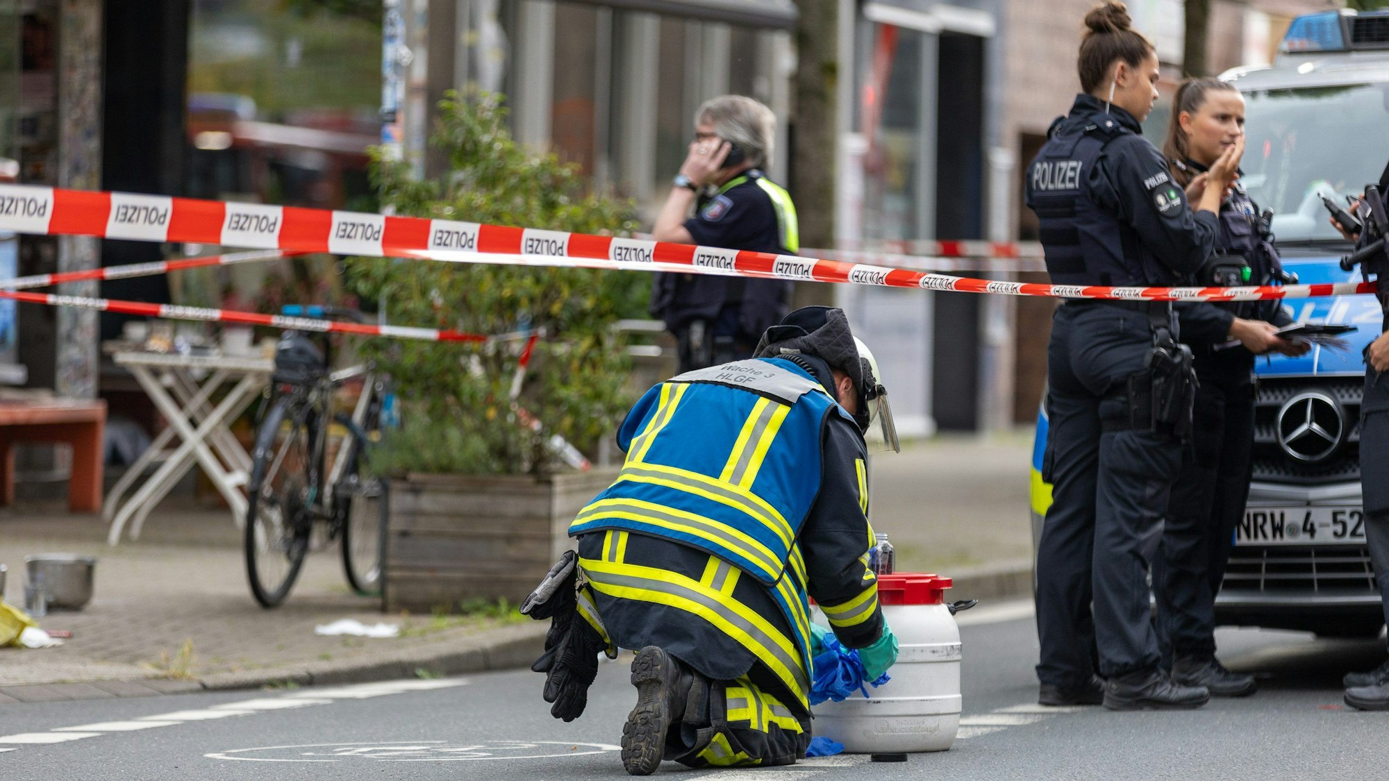 ARCHIV - 30.06.2024, Nordrhein-Westfalen, Bochum: Polizisten sind im Einsatz vor einem Bochumer Café, nachdem bei einem Angriff mit einer säurehaltigen Flüssigkeit im Außenbereich des Cafés mehrere Personen verletzt wurden.