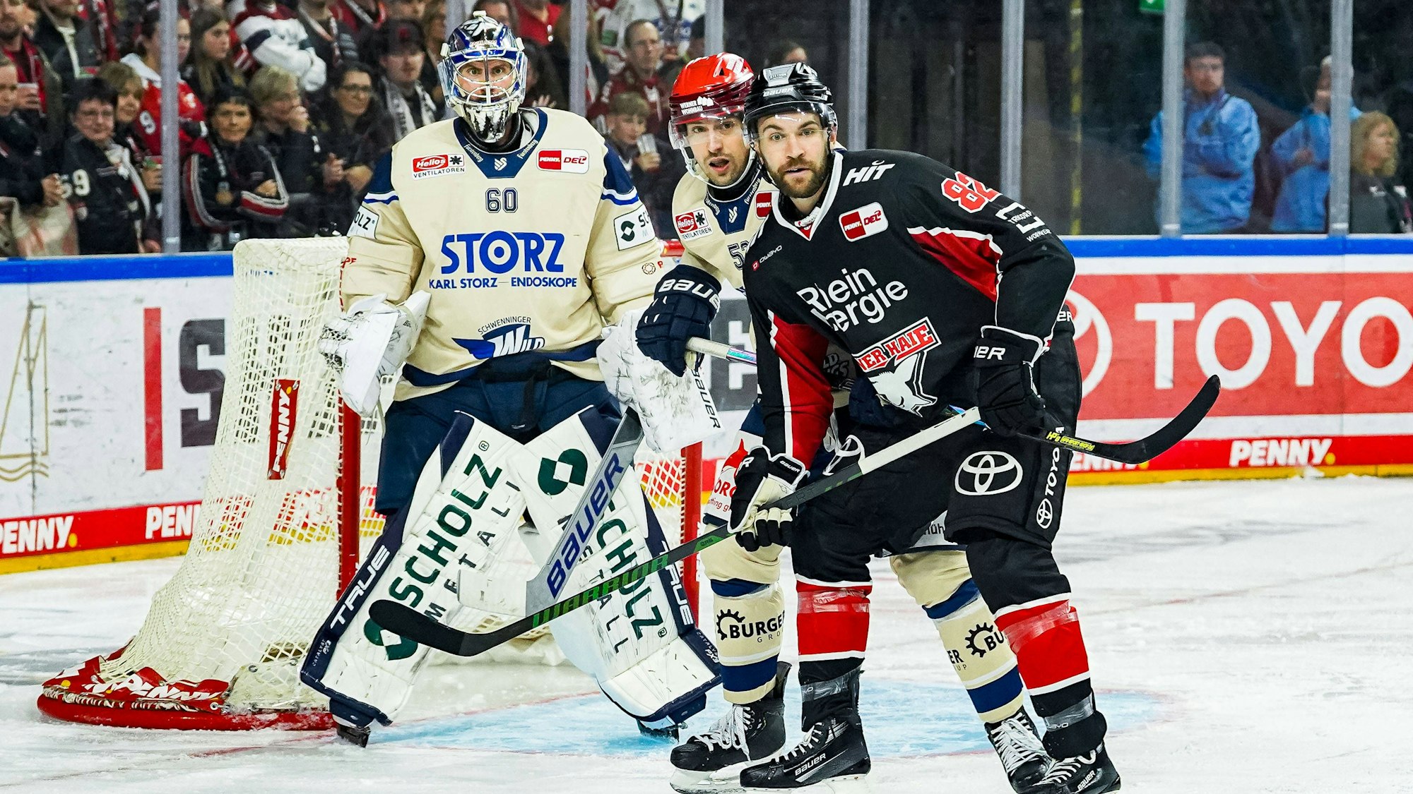 Schwenningens Torwart Joacim Eriksson (links) und Alex Trivellato verteidigen gegen Haie-Stürmer Alexandre Grenier.