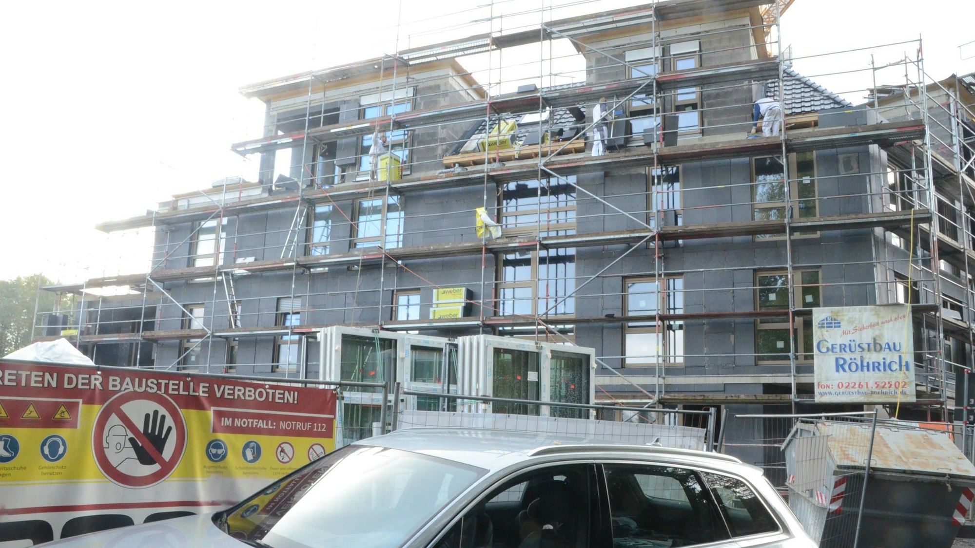 Ein mit grauem Dämmmaterial verkleideter Rohbau. Ein Schild warnt: Betreten der Baustelle verboten.