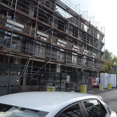 Der Rohbau für einen größeren Wohn- und Geschäftskomplex. Im Hintergrund ist der Turm einer nahen Kirche zu sehen.