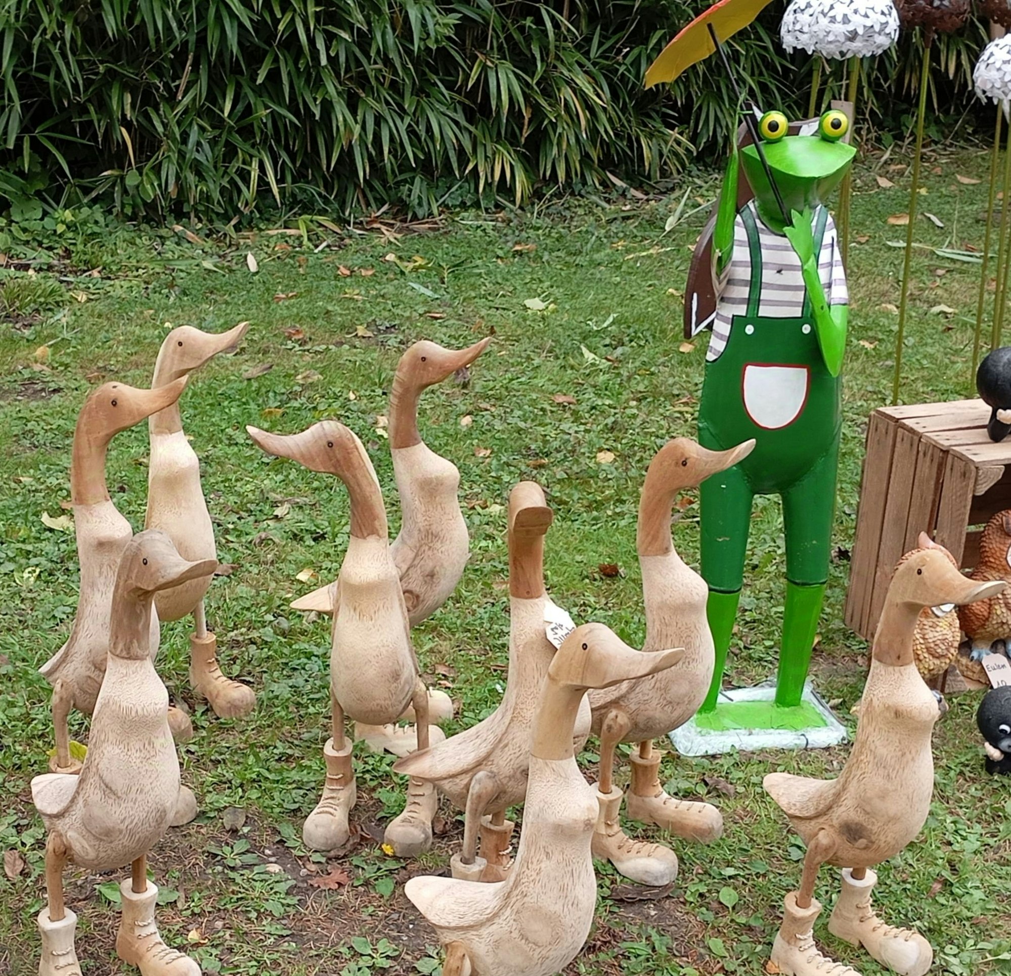 Auf dem Bild sind geschnitzte Holzenten zu sehen, die Trekkingstiefel tragen.
