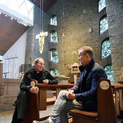 Eine Frau und ein Mann sitzen in den Bänken einer Kirche.