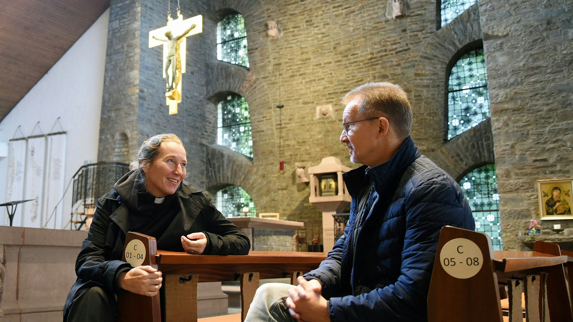 Eine Frau und ein Mann sitzen in den Bänken einer Kirche.