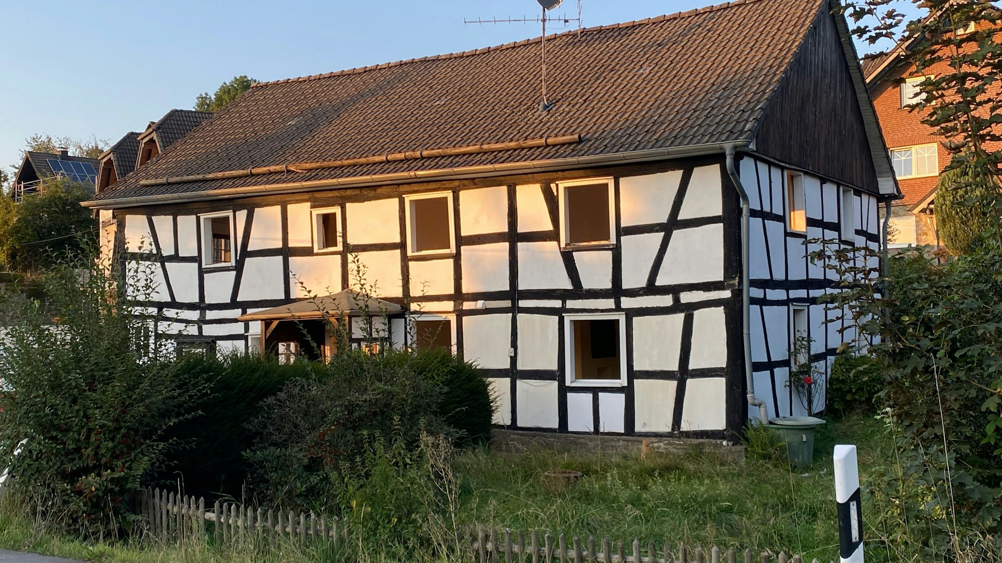Ein altes Fachwerkhaus, davor ein Garten mit Zaun.