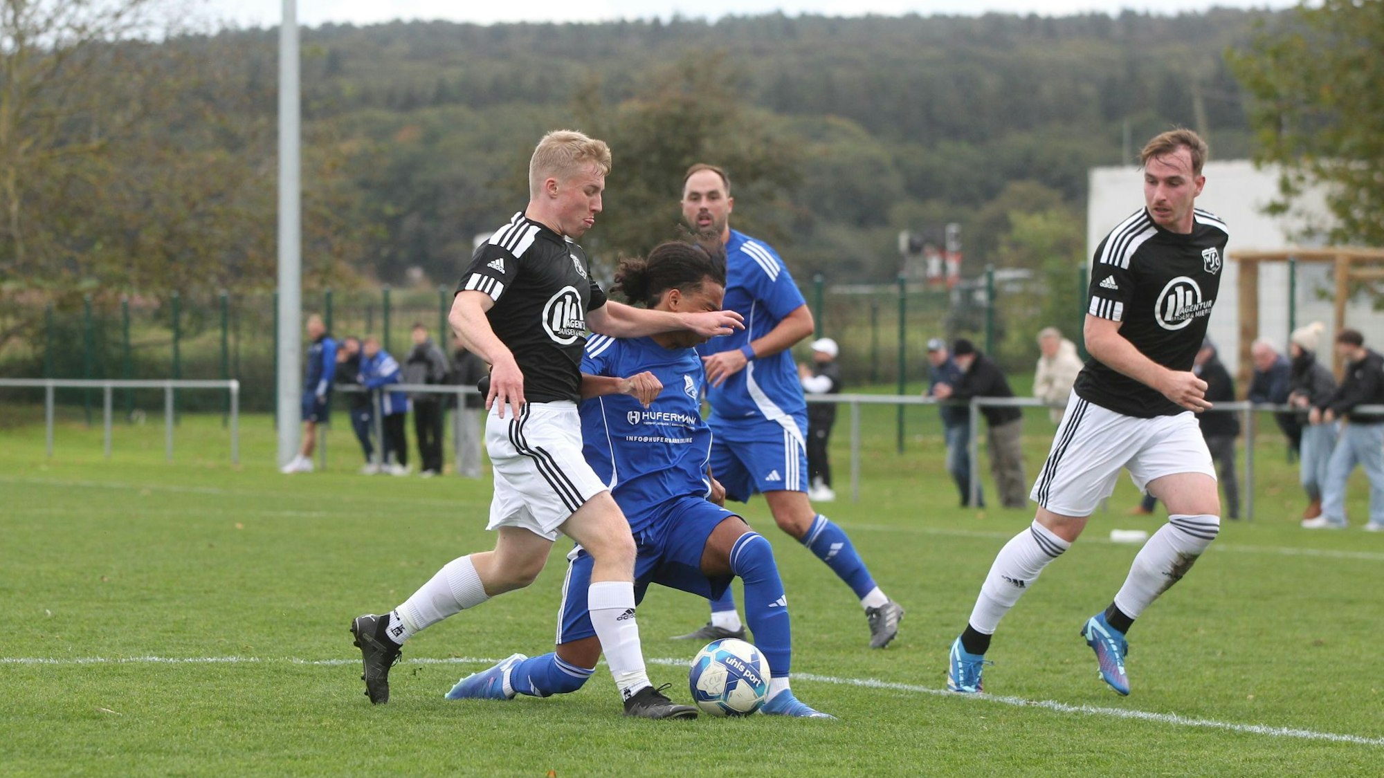 Zwei Fußballer führen einen Zweikampf, einer von ihnen lenkt den Ball zu seinem Mitspieler.