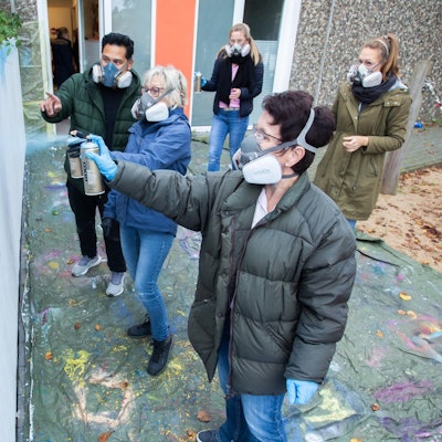 Das Foto zeigt Mitarbeiterinnen von Don Bosco und frühere Beschäftigte, die Graffiti zum Geburtstag der Kita sprayen.