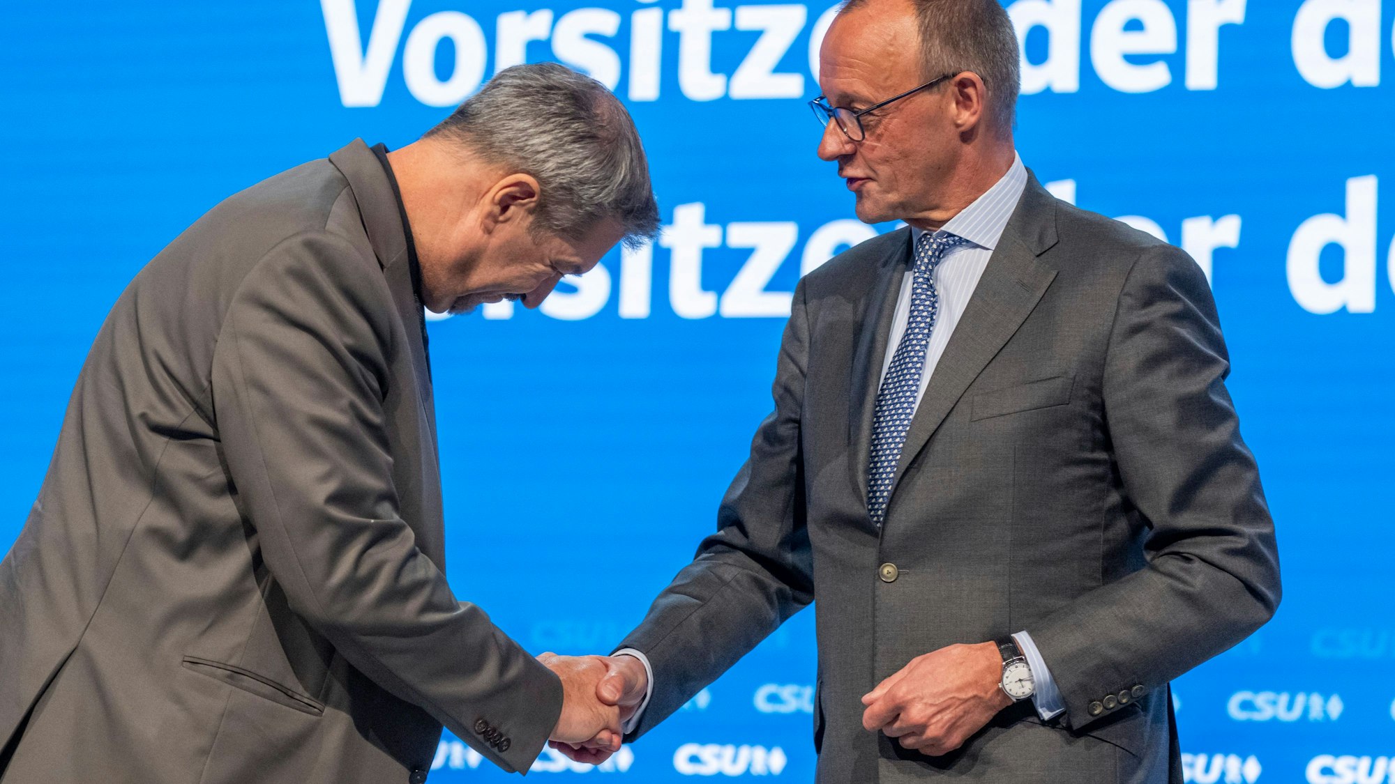dpatopbilder - 12.10.2024, Bayern, Augsburg: Markus Söder (l), Vorsitzender der CSU, gibt Friedrich Merz (r), CDU-Bundesvorsitzender und Unionsfraktionsvorsitzender, nach dessen Rede auf dem Parteitag der CSU die Hand und verbeugt sich. Foto: Peter Kneffel/dpa +++ dpa-Bildfunk +++