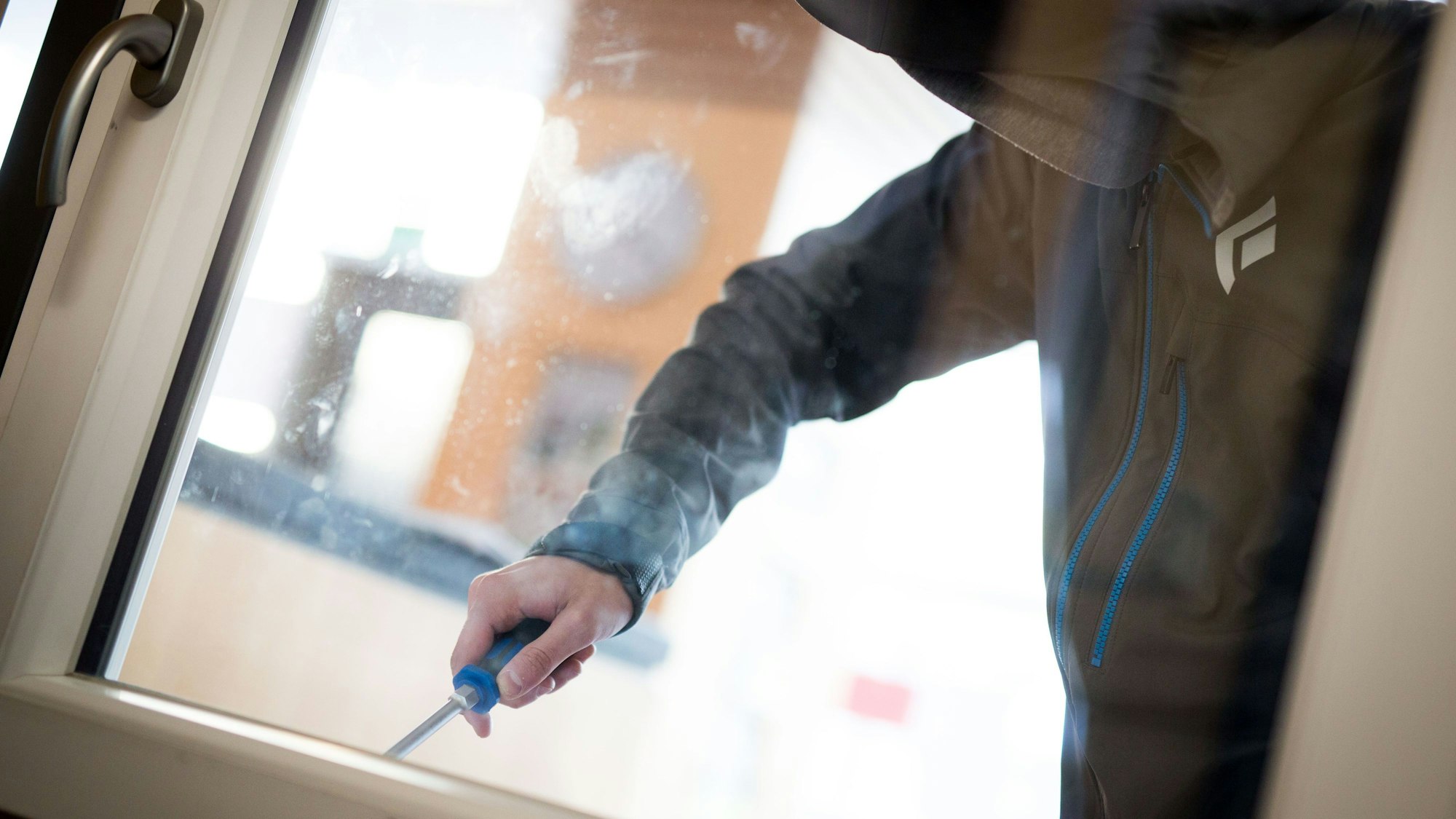 Ein Mann demonstriert in der polizeilichen Beratungsstelle, wie einfach es für einen Einbrecher wäre, mit Hilfe eines stabilen Schraubenziehers ein geschlossenes Fenster von außen zu öffnen.