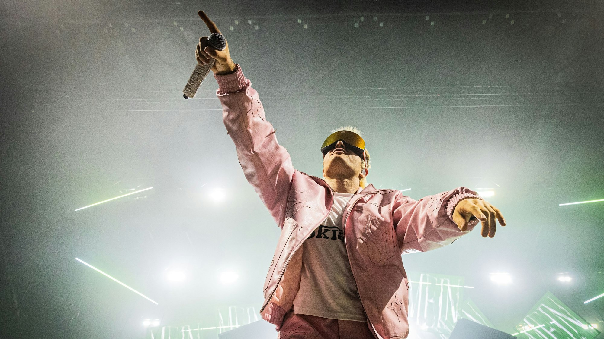 Ski Aggu steht mit pinker Jacke und Skibrille auf der Bühne.