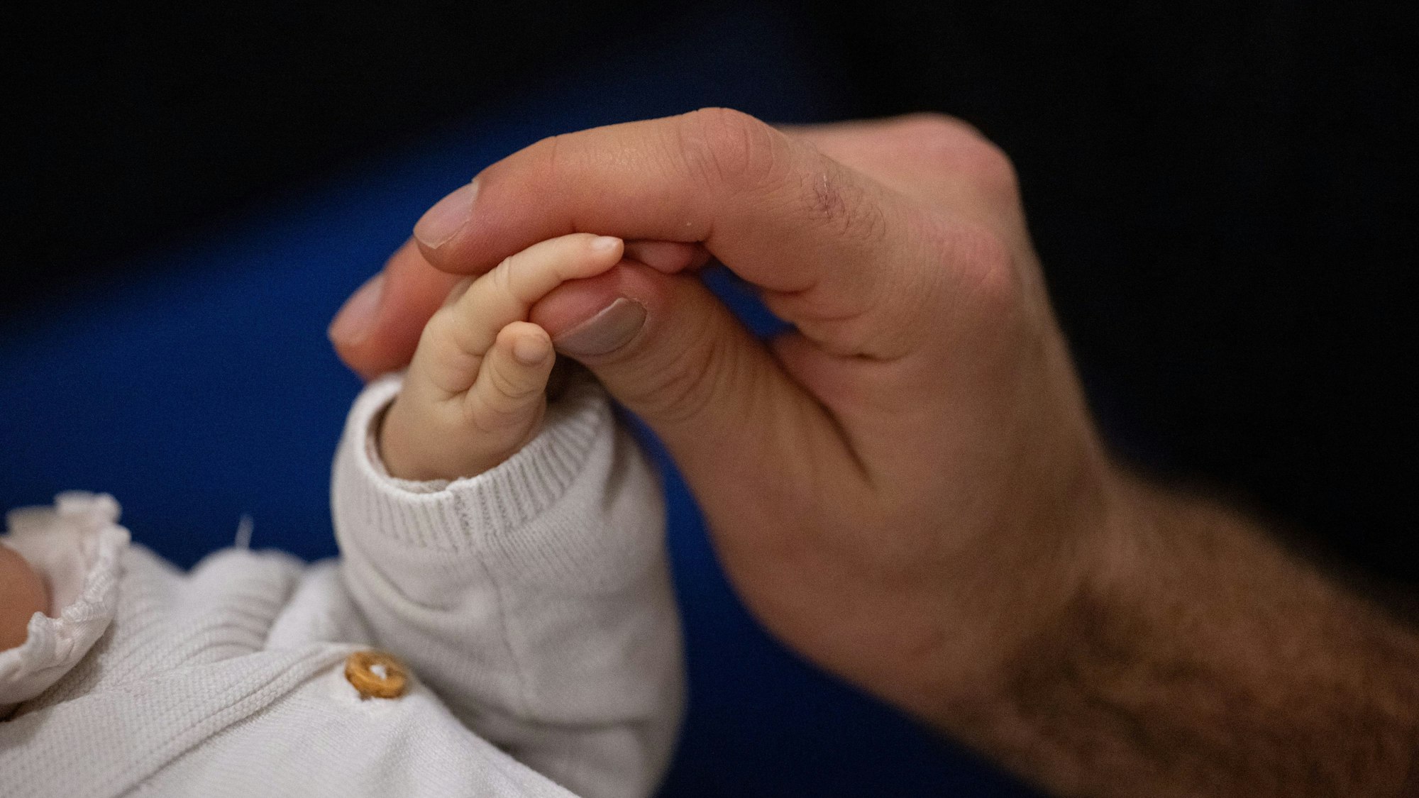 Ein Vater berührt während eines Infant Handling Kurses die Hand seines Kindes.