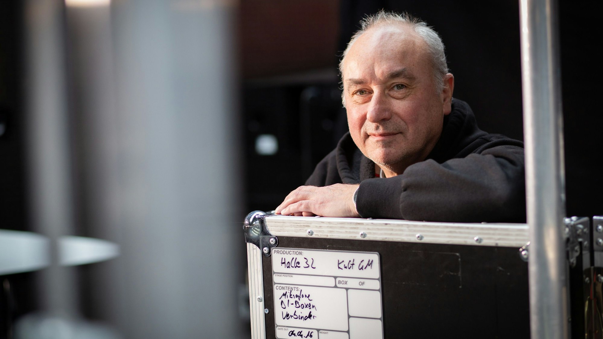 Der Porträtierte lehnt auf einer Bühnenkiste.