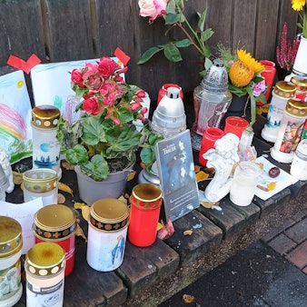 Auf einer Bank haben Pulheimer Anwohner Kerzen, Blumen, Bilder und Briefe abgelegt.