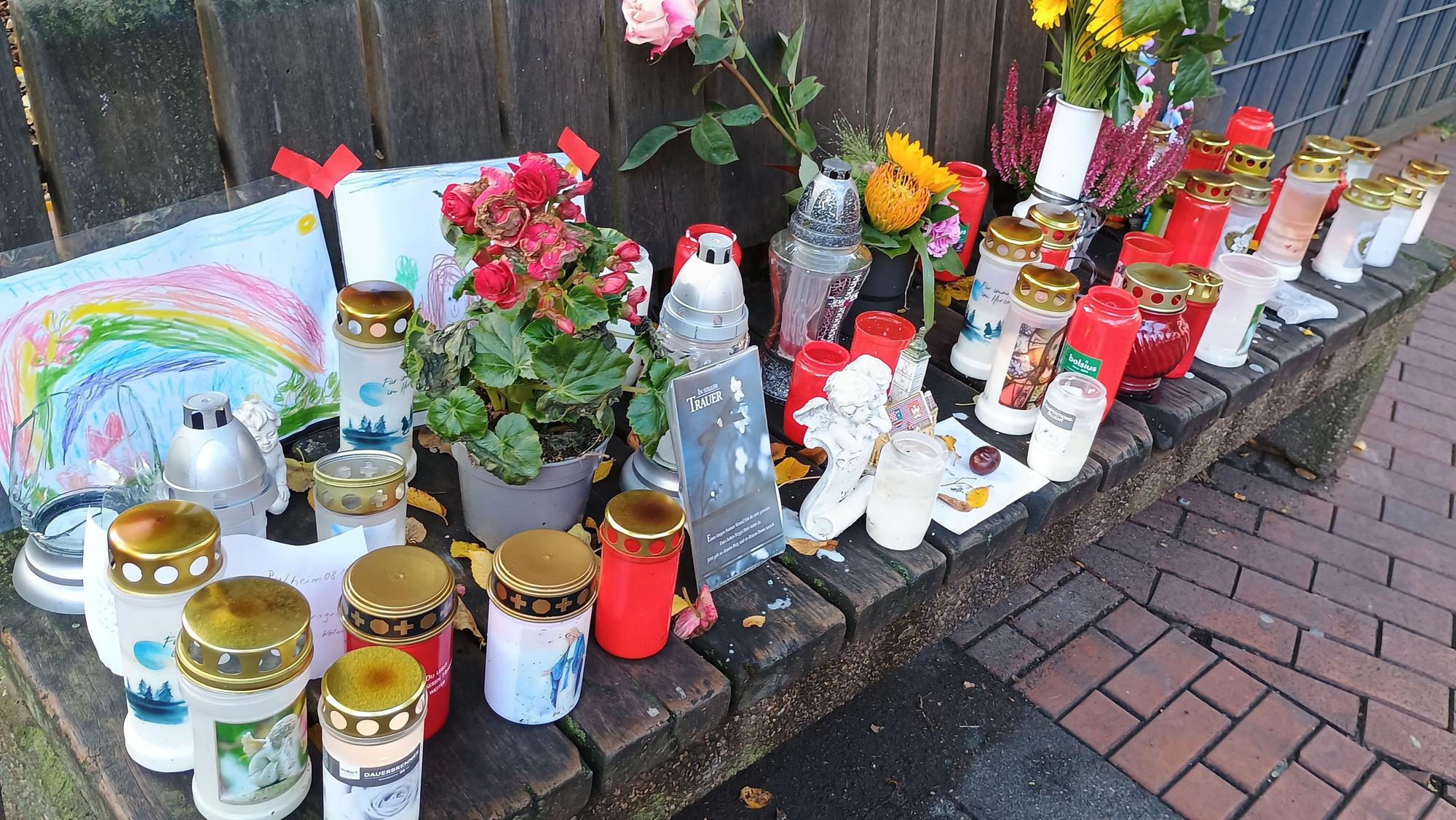 Auf einer Bank haben Pulheimer Anwohner Kerzen, Blumen, Bilder und Briefe abgelegt.