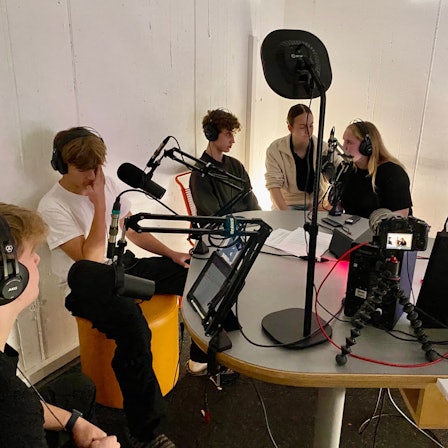 Jugendliche sitzen in einem Aufnahmestudio.