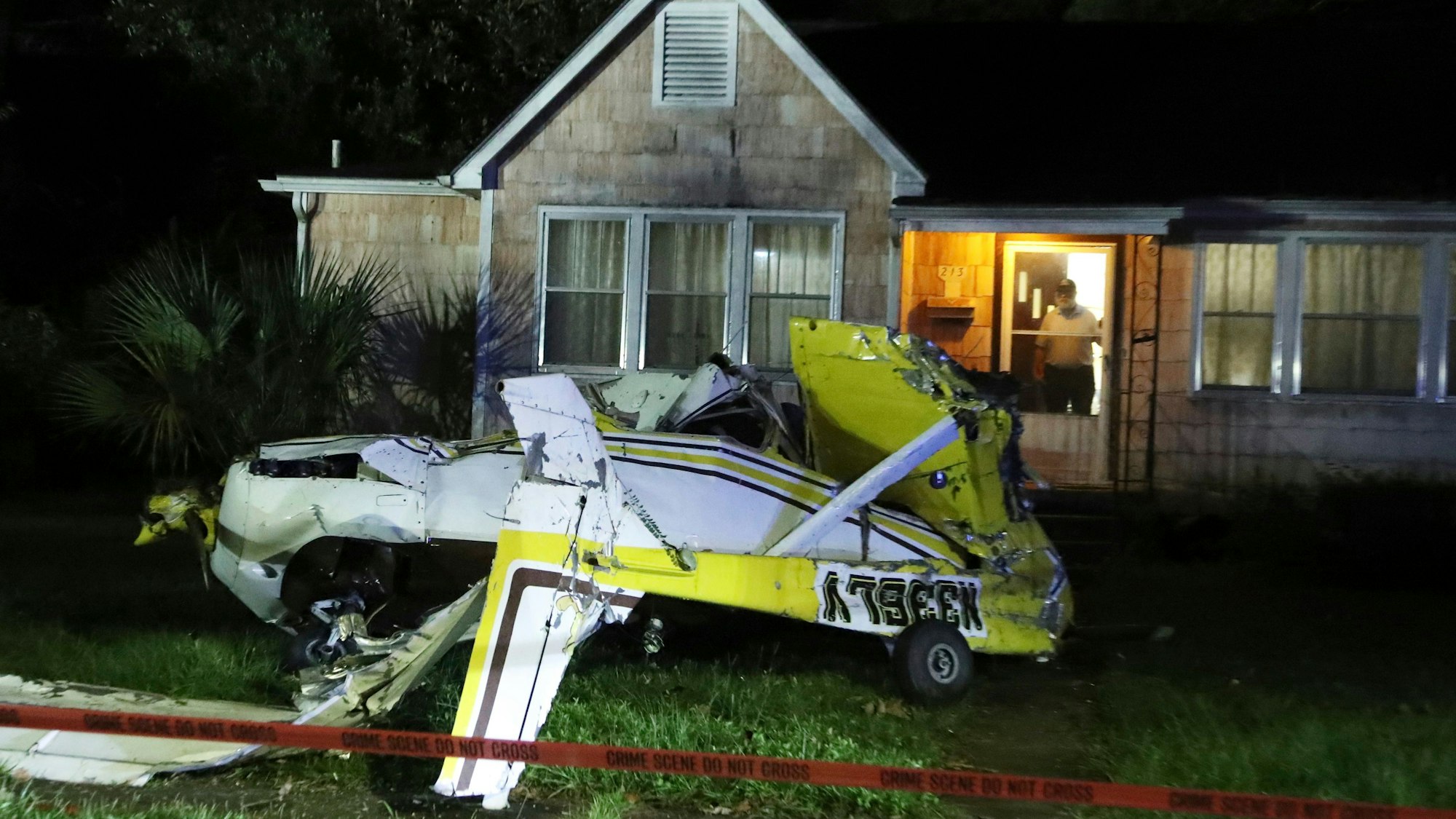 Ein Mann schaut aus der Eingangstür seines Hauses, nachdem eine Cessna in Savannah, Georgia, in den Vorgarten gestürzt ist.